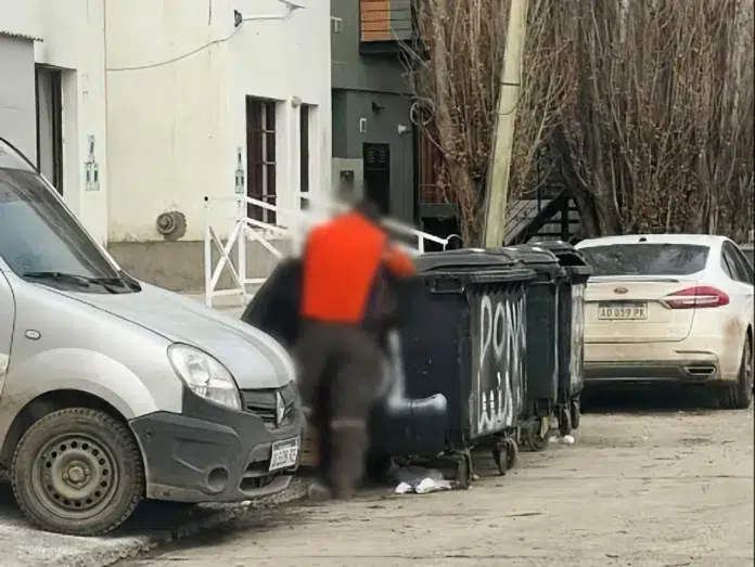 Una persona busca comida en un contenedor de basura en El Calafate - Una persona busca comida en un contenedor de basura en El Calafate -